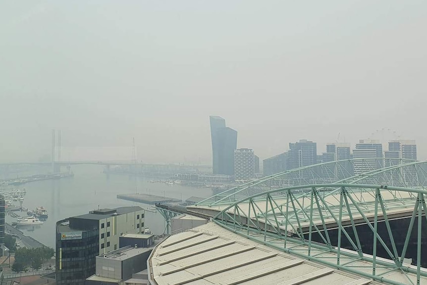 A haze hangs over Melbourne's CBD, viewed from several storeys high in an apartment.