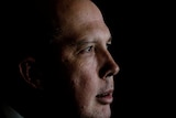 Mr Dutton is in profile, against a black background.
