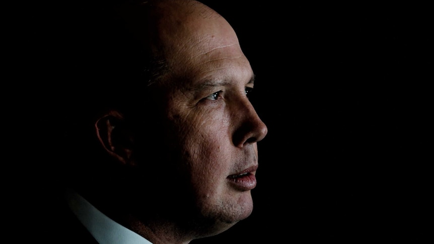 Mr Dutton is in profile, against a black background.