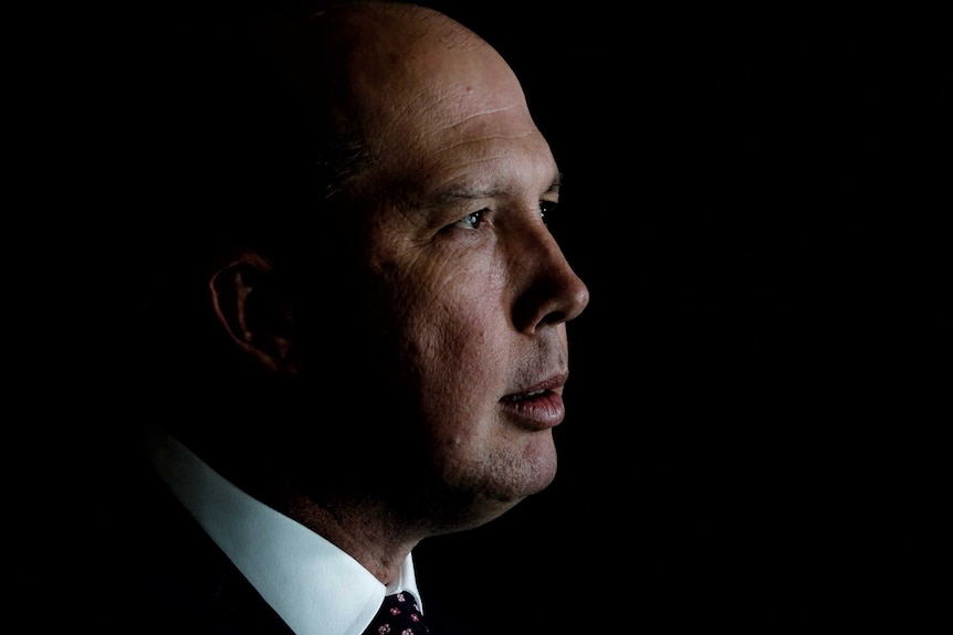 Mr Dutton is in profile, against a black background.