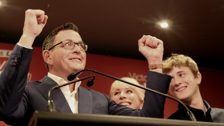 Daniel Andrews pumps his fists in the air as he claims victory in the Victorian election. He is surrounded by his family