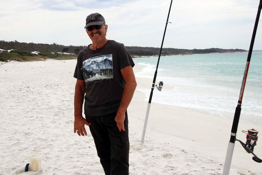 Jack standing near his fishing rods at Swimcart Beach on Tasmania's East Coast