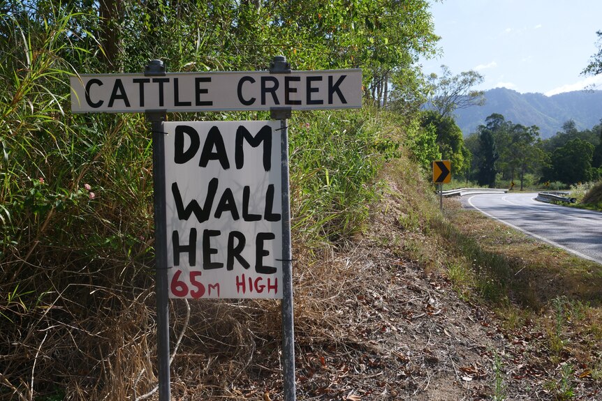 A sign on the side of the road that reads "Dam Wall here 65m high"
