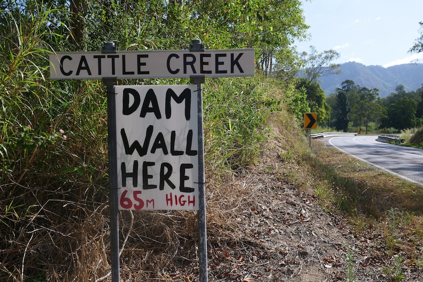 A sign on the side of the road that reads "Dam Wall here 65m high"