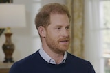 A close up of Prince Harry wearing a sweater with the collar peeping through.