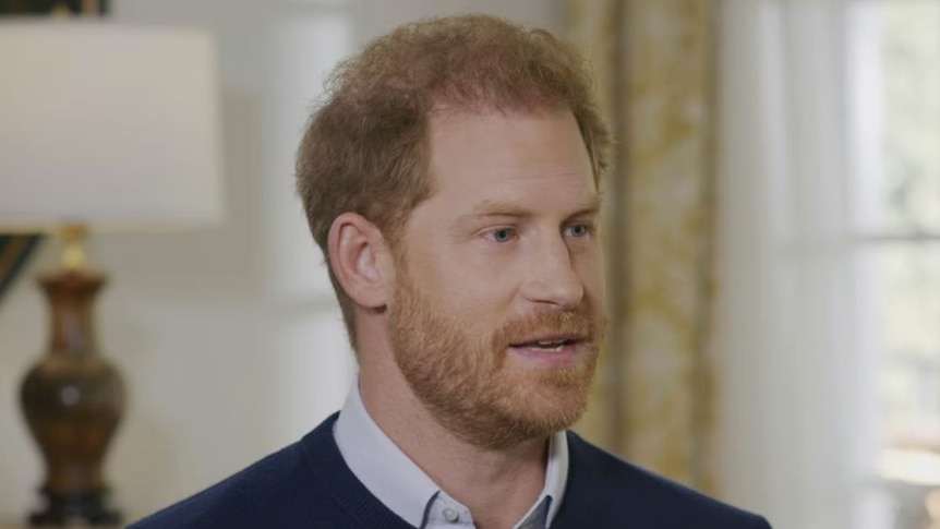 A close up of Prince Harry wearing a sweater with the collar peeping through.