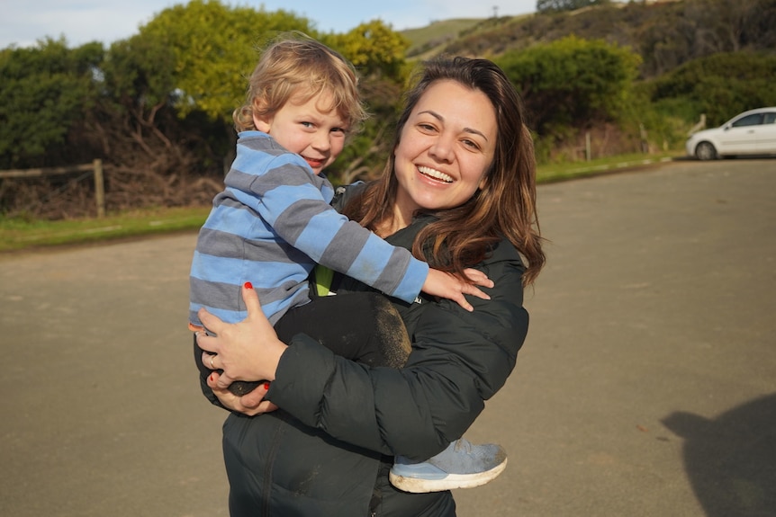 A young woman holds her young son