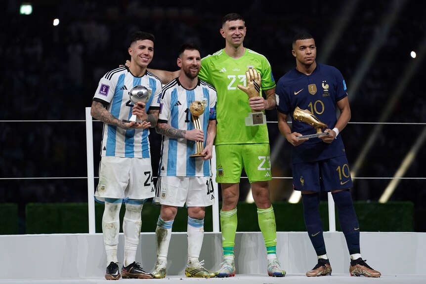 Enzo Fernández, Lionel Messi, Emiliano Martínez de Argentina y Kylian Mbappe de Francia posan con trofeos individuales.