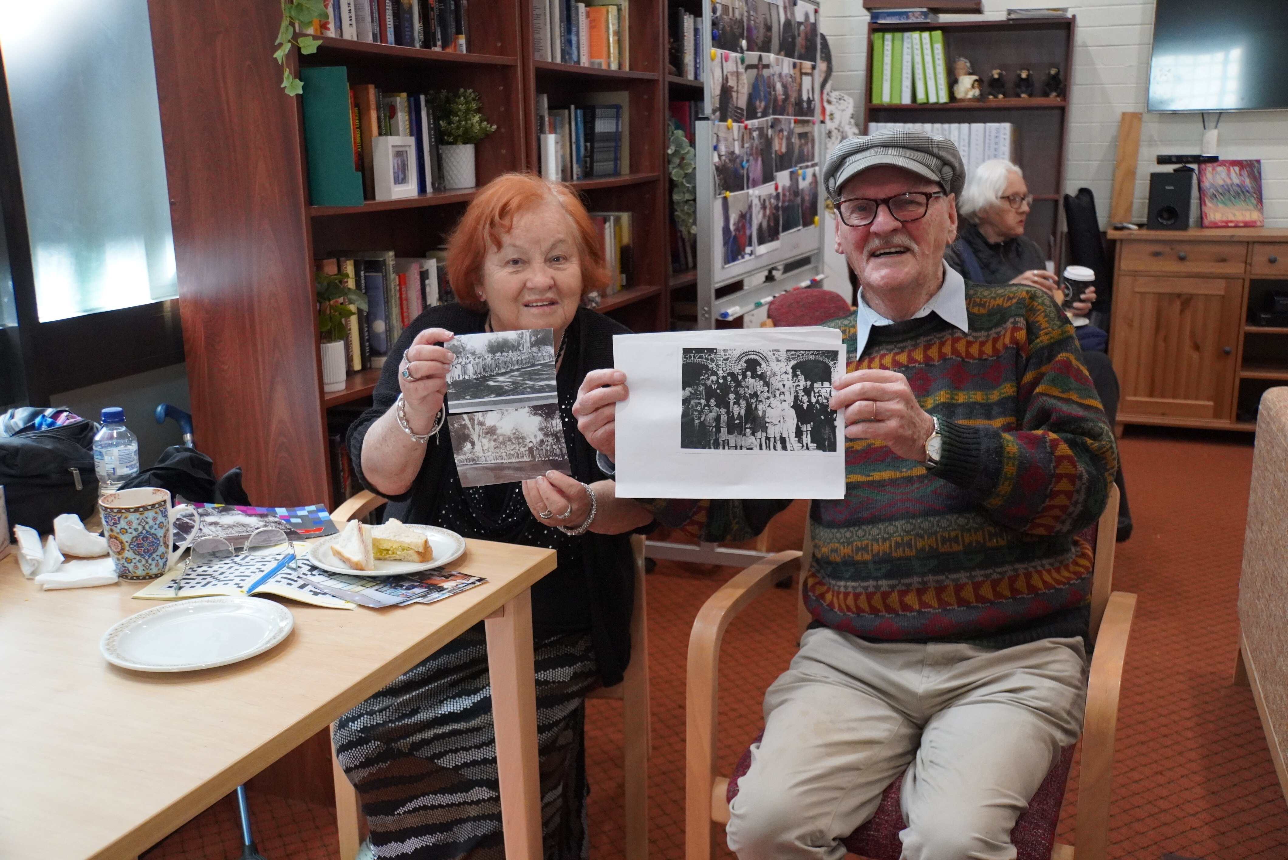 woman and man sit together holding up black and white photos