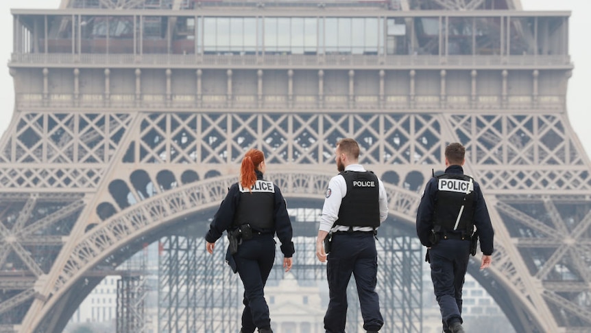 Three police officers patrol outside the Eiffel Tower.