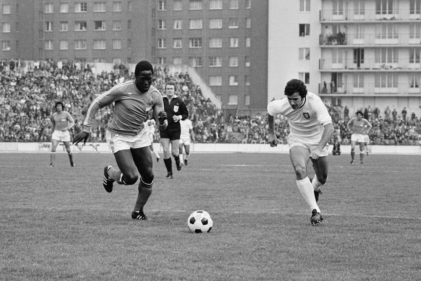 A black and white photo of French defender Jean-Pierre Adams and Portugal's Baptista Tamagnini Nene chase the football.