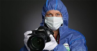 Woman in protective clothing holds camera.