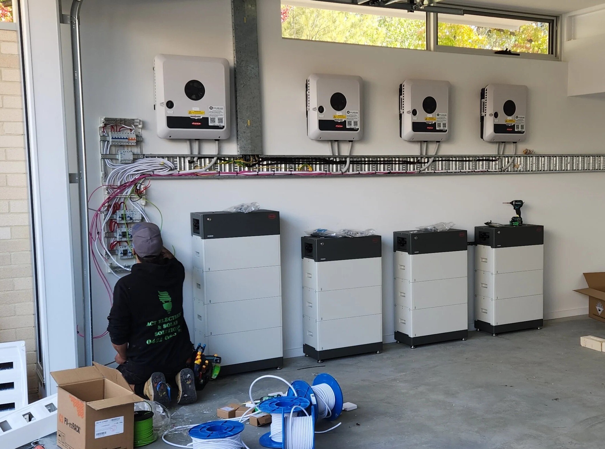 Solar batteries line the wall inside a room, connected by wires.