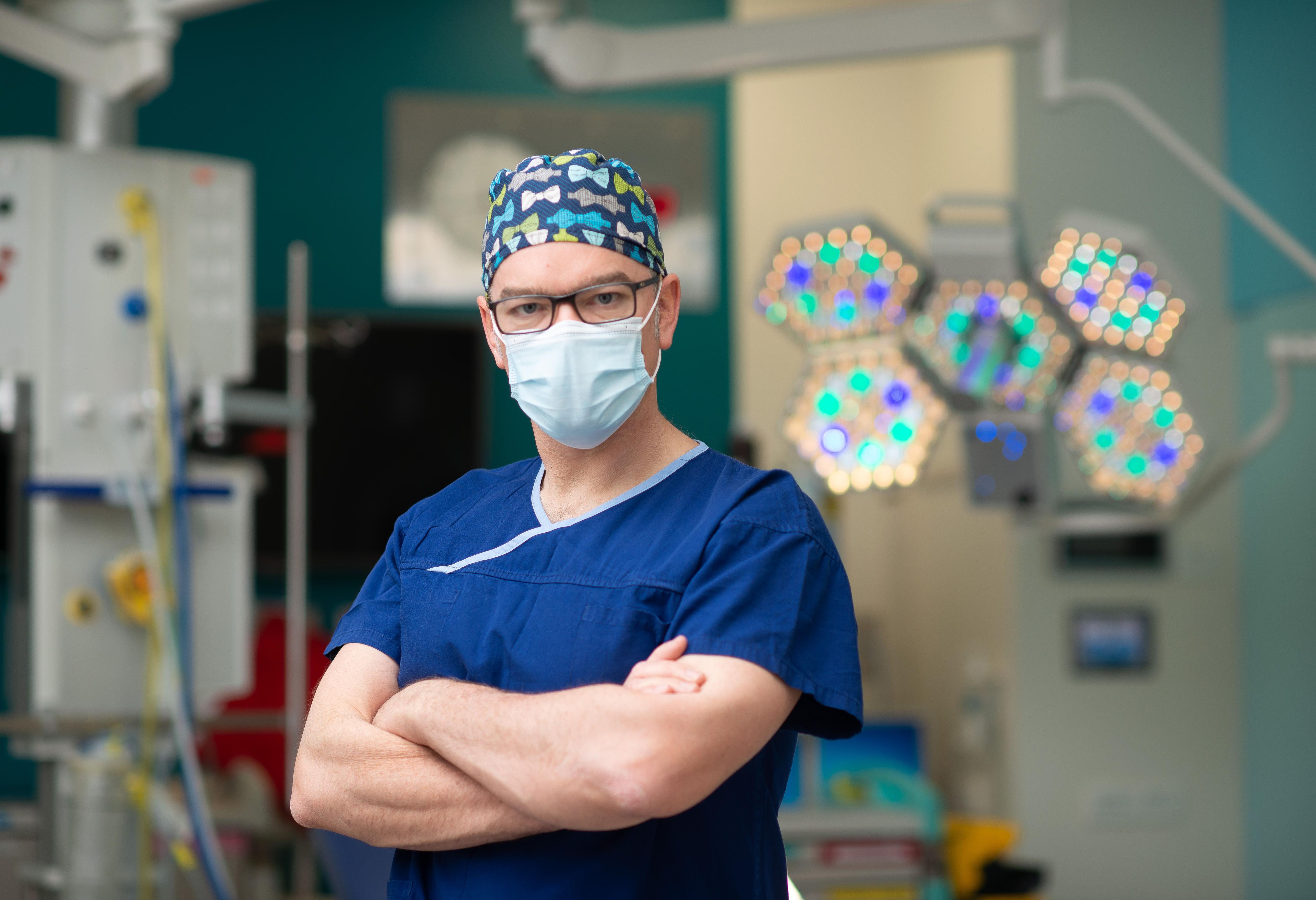 A man in scrubs and a mask standing in a hospital.