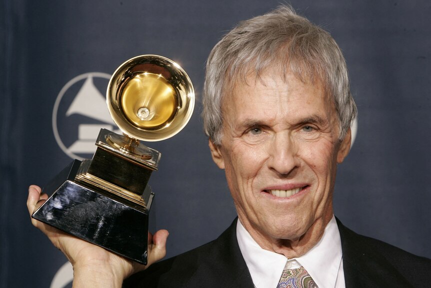 Close up of man holding up Grammy award next to his face.