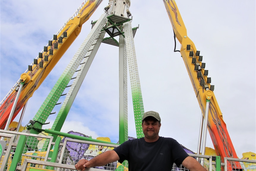 Jamie Picket standing underneath a giant mechanical pendulum ride 