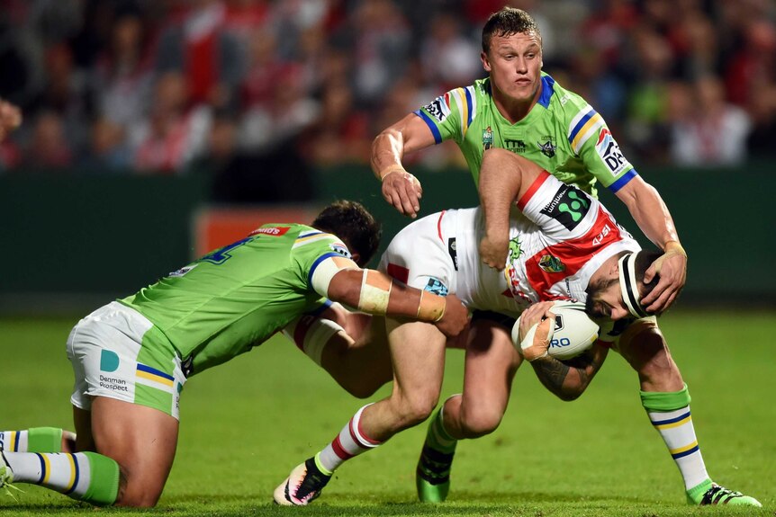 Jacob Marketo (right) of the Dragons is tackled by Josh Papalli (left) and Jack Wighton of the Raiders