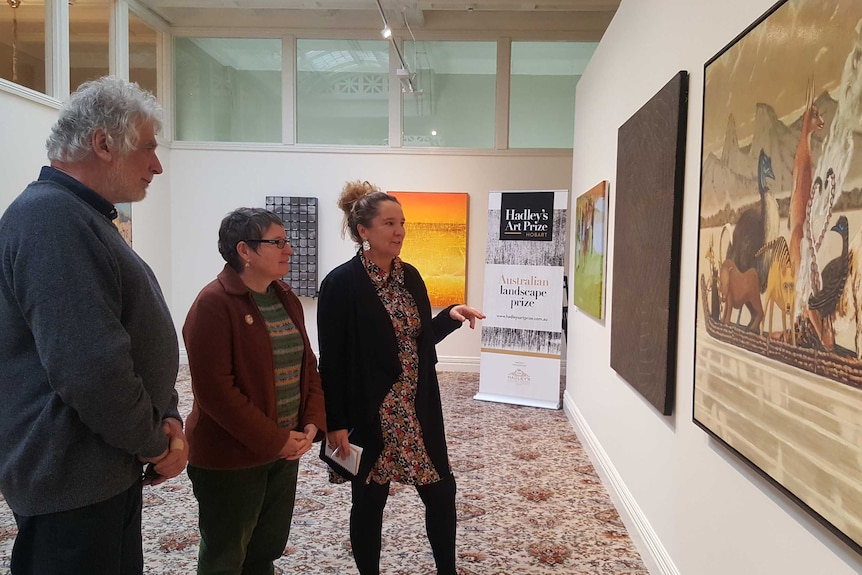 Judges Roger Butler, Dr Julie Gough and Lisa Slade look at an artwork.