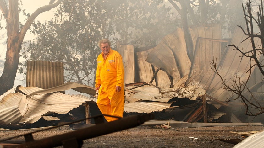 A farmer inspects the ruins of his ravaged homestead