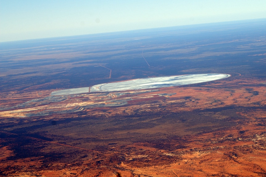 An aerial shot of red earth and a tailings dam 