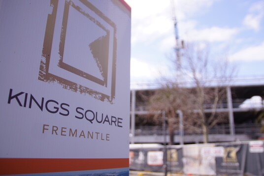 A sign saying Kings Square, Fremantle with building construction and a crane in the background.
