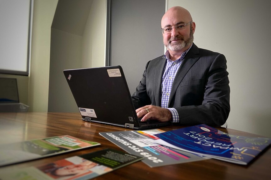 Paul Edginton sits at a desk in front of his laptop.