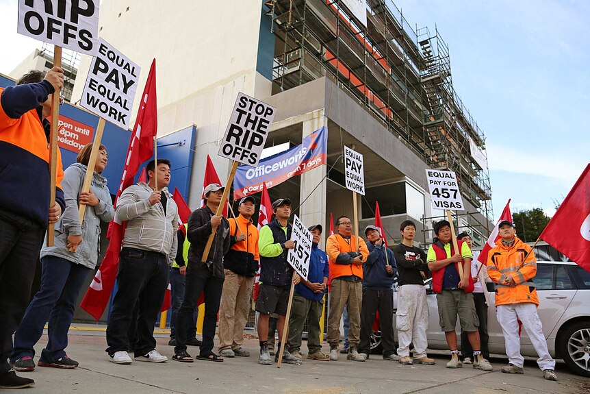Workers carrying signs outside a Braddon protest claiming 457 visa holders are being underpaid.