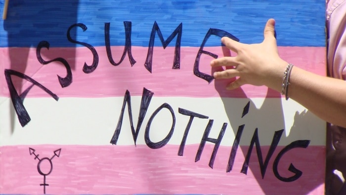 A marcher at the 2011 San Francisco Pride carries a poster that reads, 'Assume nothing'.