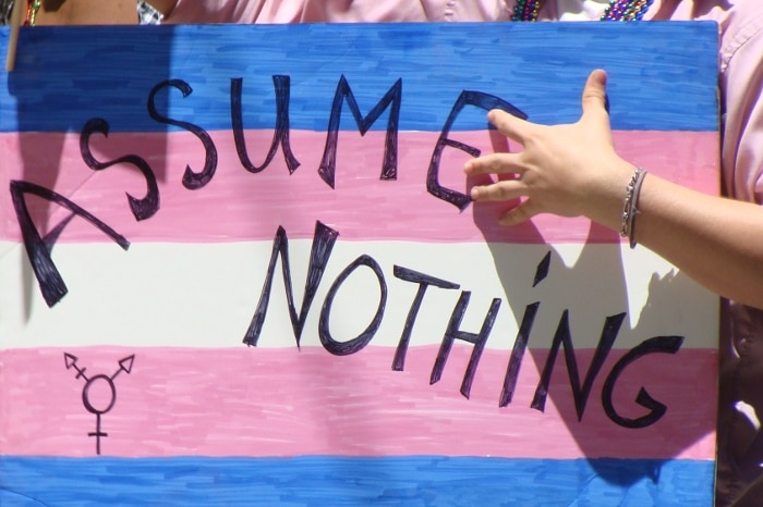 A marcher at the 2011 San Francisco Pride carries a poster that reads, 'Assume nothing'.