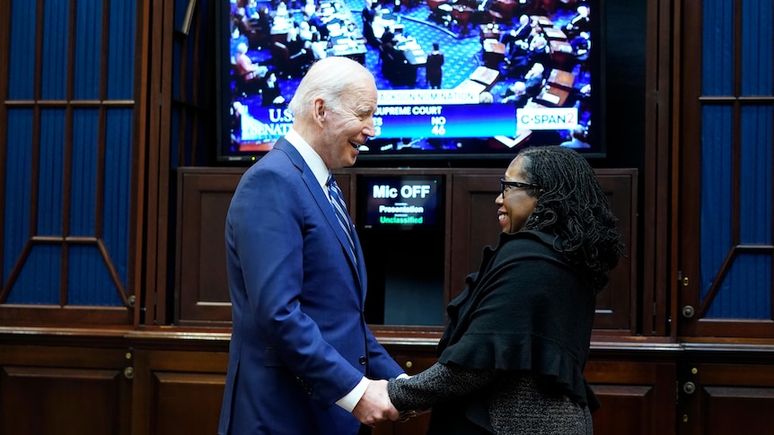 President Joe Biden holds hands and talks with Supreme Court nominee Judge Ketanji Brown Jackson as they watch the Senate vote.