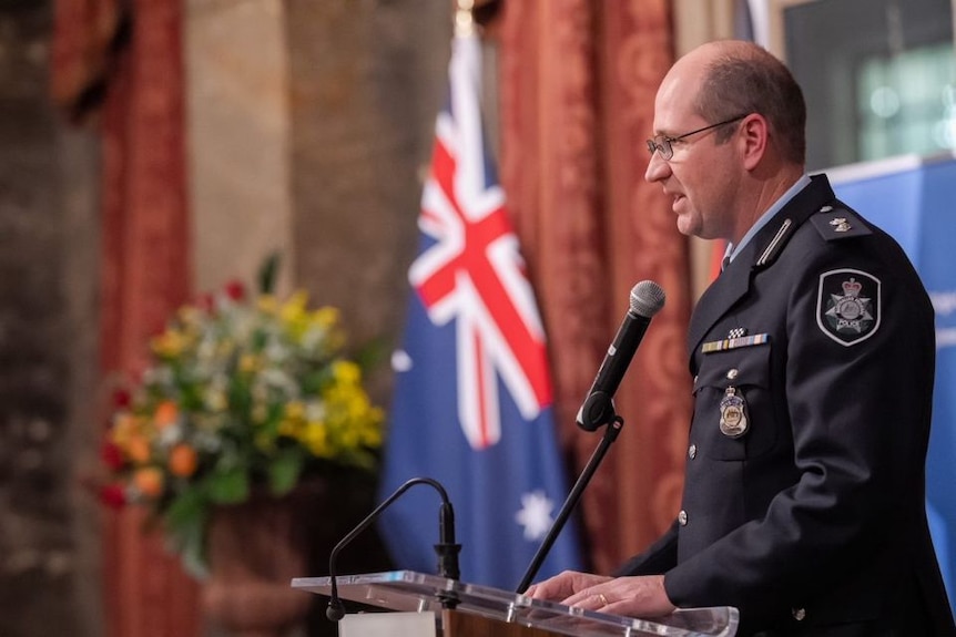 Man in police uniform speaking at a lectern 