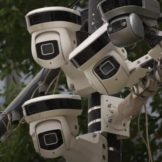 A group of surveillance cameras on a pole.