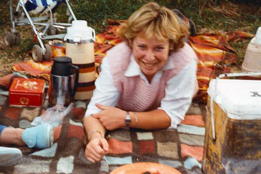 A 1980s photograph of a teenage girl lying on a picnic blanket