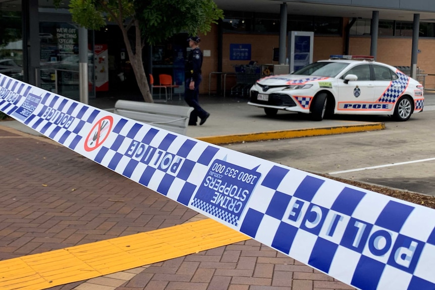 Police tape, police car and police officer outside Aldi supermarket where girl was shot with bow and arrow