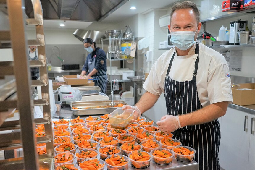 Volunteers in ARK Centre's kitchen, wearing masks, making food to deliver to people in Melbourne.