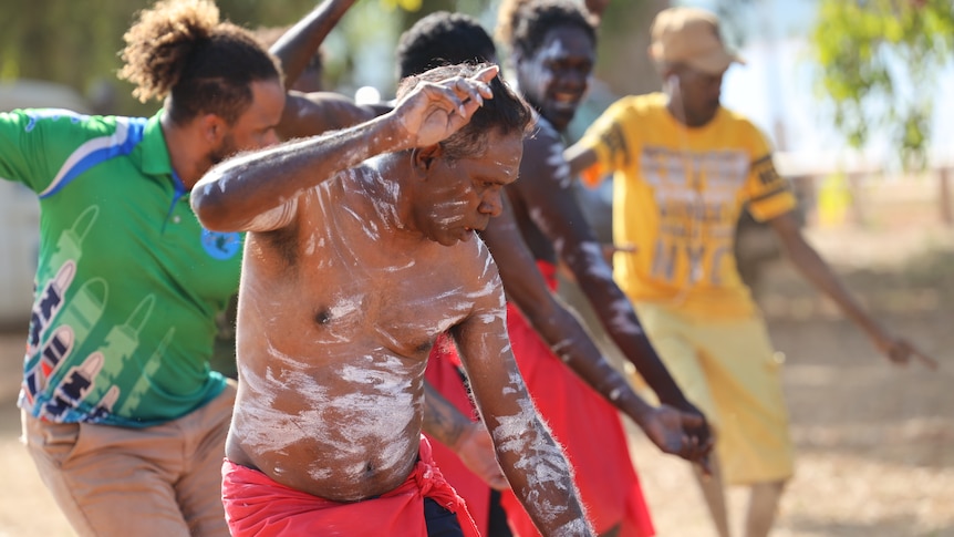 Four Aboriginal men, some with their bodies painted, perform a cultural dance