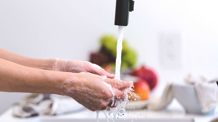 Woman's holding and washing a kitchen item in a kitchen sink.