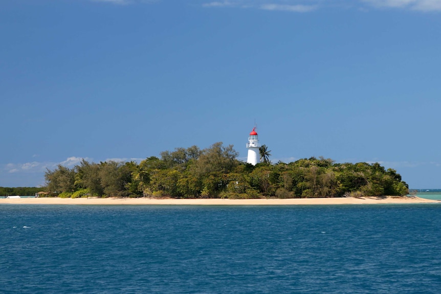 Photo of sandy tropical island called Low Island and a red and white lighthouse off the coast of Port Douglas.