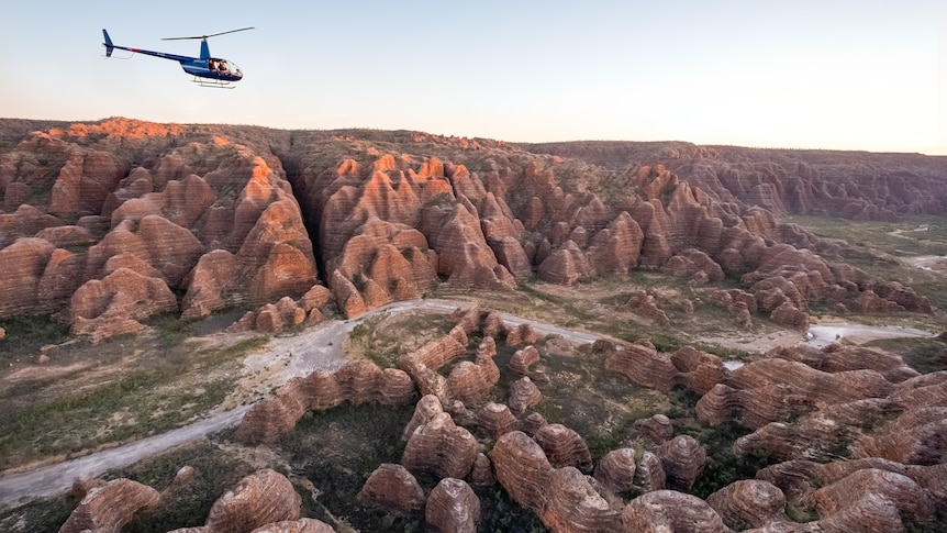 helicopter flies above beehive-like  rock formations 