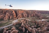 helicopter flies above beehive-like  rock formations 