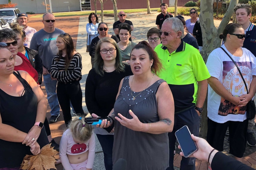 A woman standing in a group of about 20 people speaking in protest,  in Eaton.