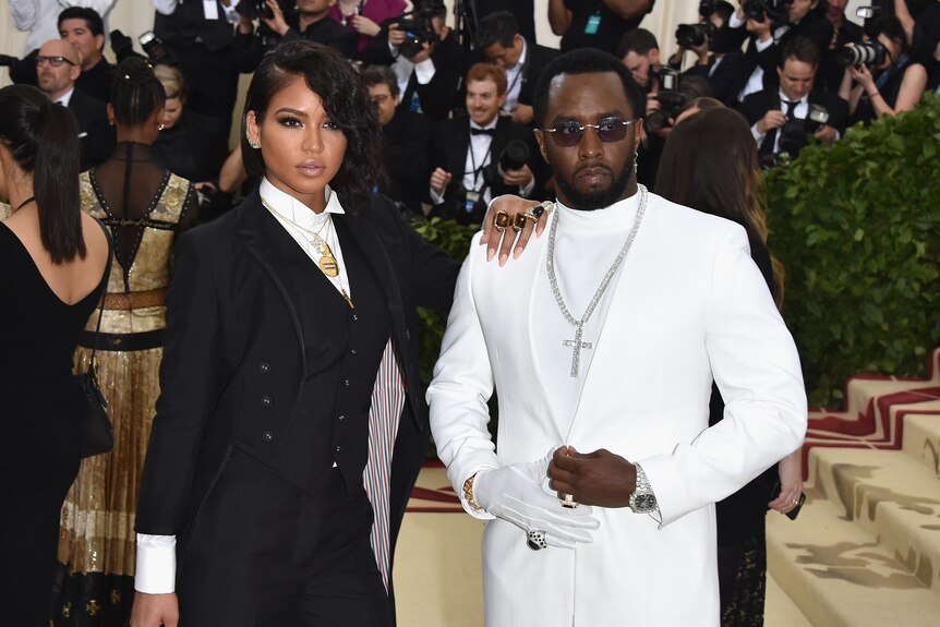 Cassie wearing a black suit with short hair, her hand on Sean "Diddy" Combs's shoulder. He's in a white suit and silver crucifix