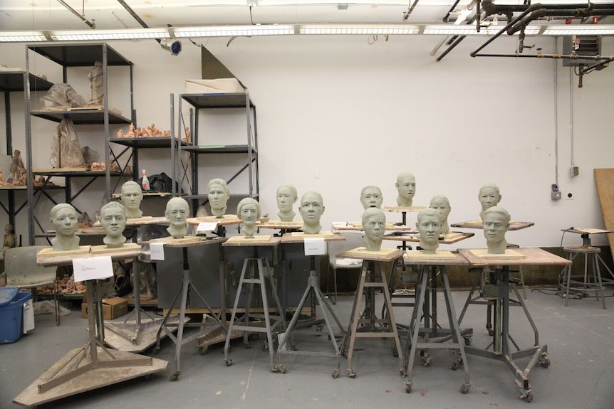 A group of sculpted faces in an art studio.