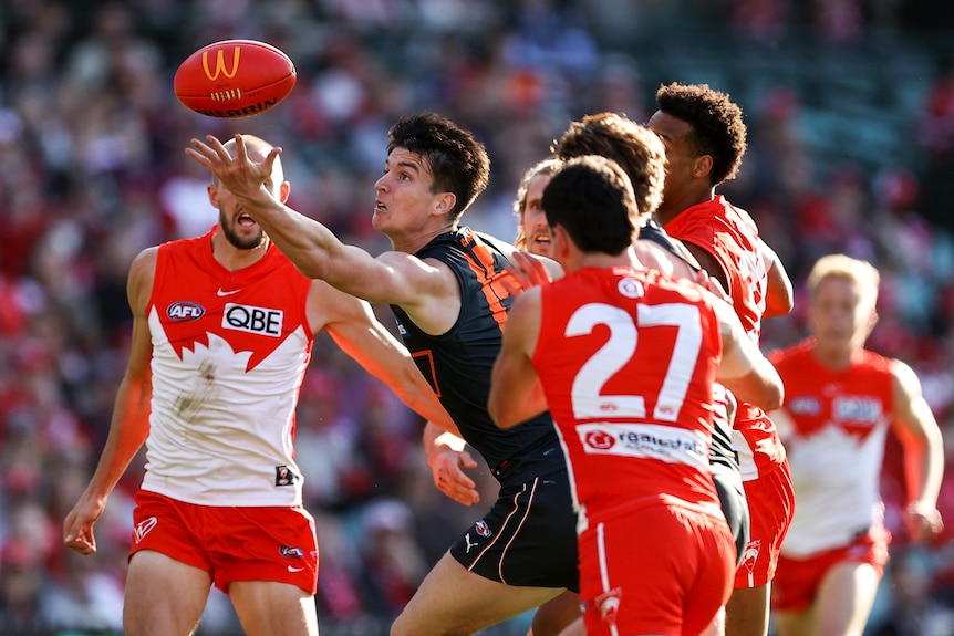 Sam Taylor reaches for the ball while surrounded by three Swans players