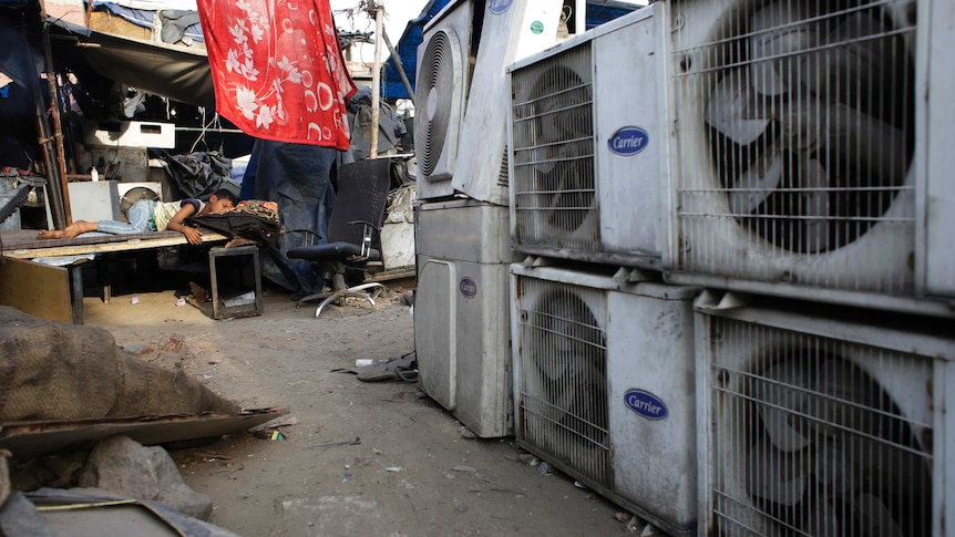 An Indian boy sleeps in scorching heat near an air conditioner shop in New Delhi, India