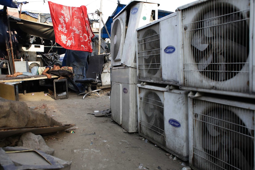 An Indian boy sleeps in scorching heat near an air conditioner shop in New Delhi, India