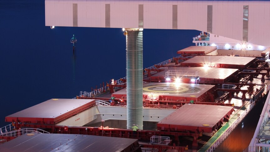 An enormous pipe shifts grain into a large cargo ship