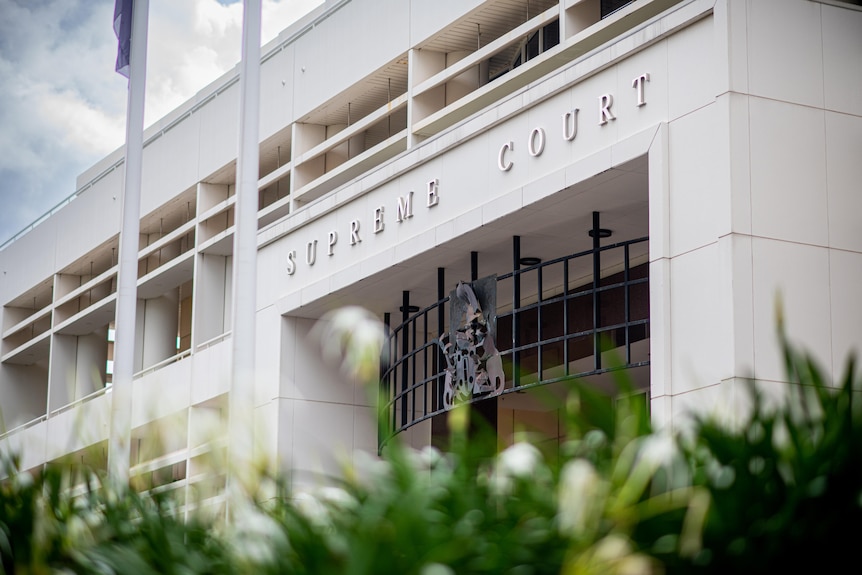 A white, modernist, flat-fronted building with "supreme court" in capital letters above a wide entrance.