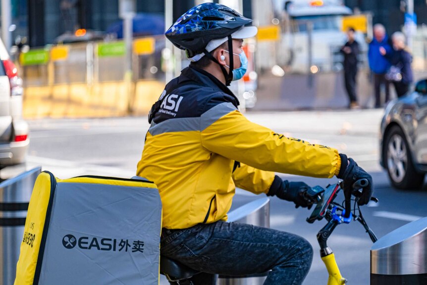 EASI Food delivery person on a bike waiting to cross the street