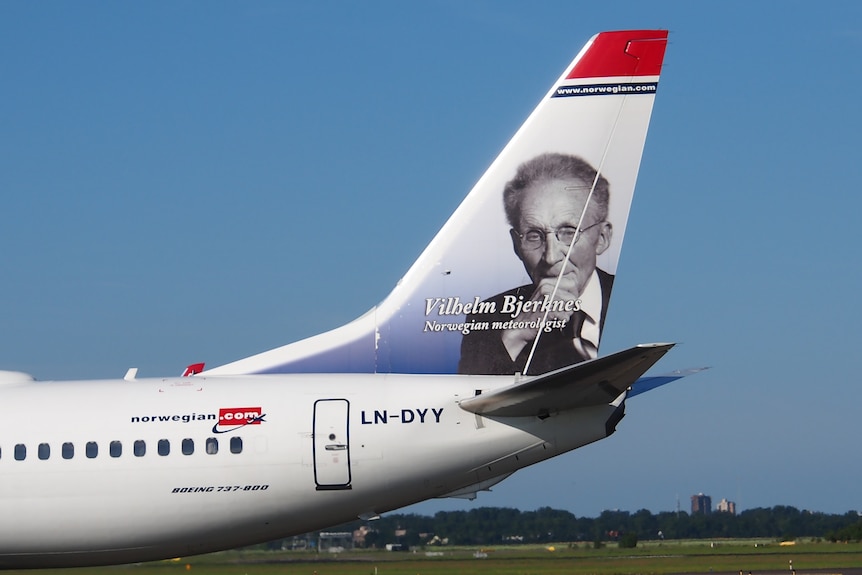The tail of a plane with an image of a elderly Norwegian man on it.
